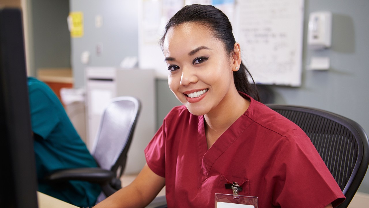 Portrait Of Female Nurse Working At Nurses Station